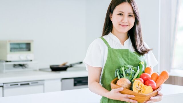 届いた野菜をキッチンに運ぶ女性
