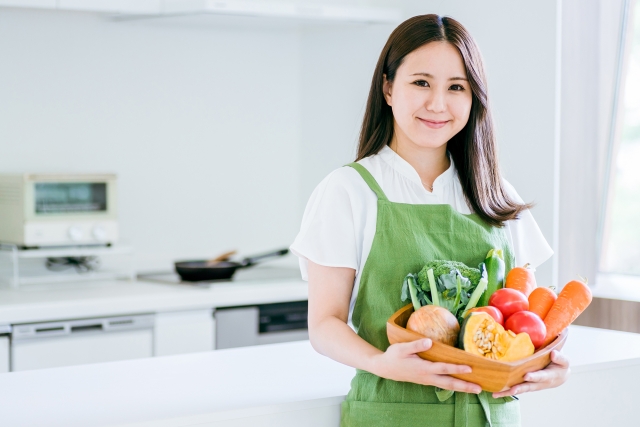 届いた野菜をキッチンに運ぶ女性