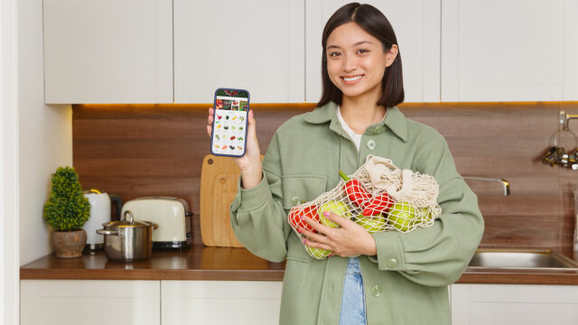 スマートフォンで果物を選びながら買い物する女性