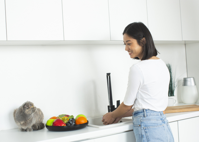 キッチンで果物を洗う女性の様子｜家庭でできる農薬対策のイメージ