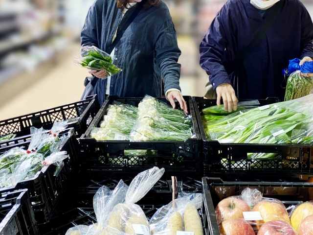 売り場で葉物野菜を選ぶ人達