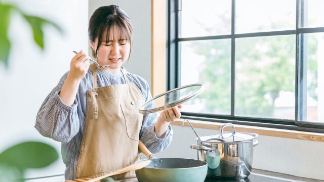 味見をしたら失敗した表情を見せる料理をする女性